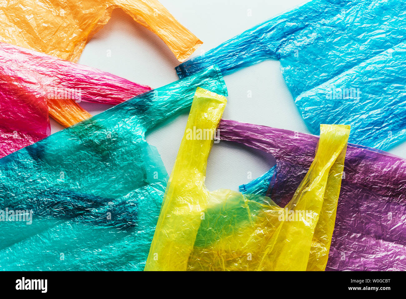 Diversi colori luminosi sacchetti di plastica usa e getta sul piano. Ecologia promemoria. Società di consumo. Immagine concettuale. Foto Stock