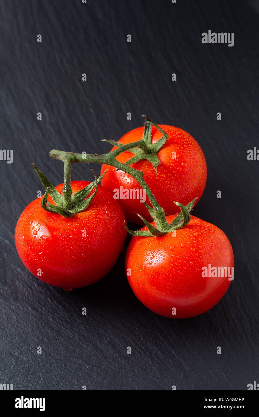 Concetto di cibo organico di pomodori in ardesia nera con scheda spazio di copia Foto Stock