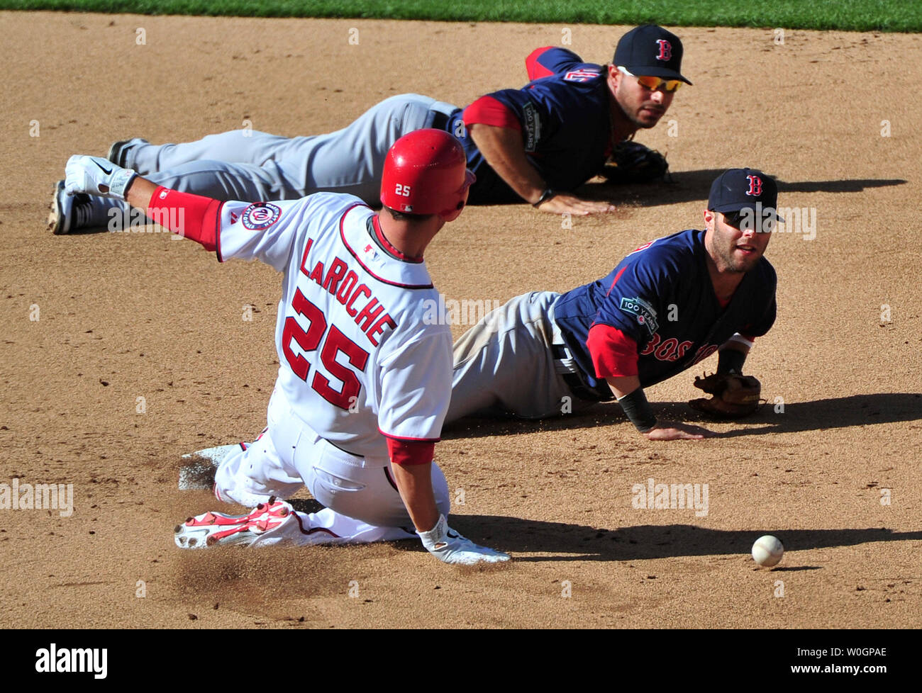 Cittadini di Washington Adam LaRoche scorre nella seconda come Boston Red Sox interbase Mike Aviles (top) e secondo baseman Dustin Pedroia mishandle una palla durante il sesto inning della loro esposizione al gioco cittadini Park a Washington D.C. il 3 aprile 2012. UPI/Kevin Dietsch Foto Stock