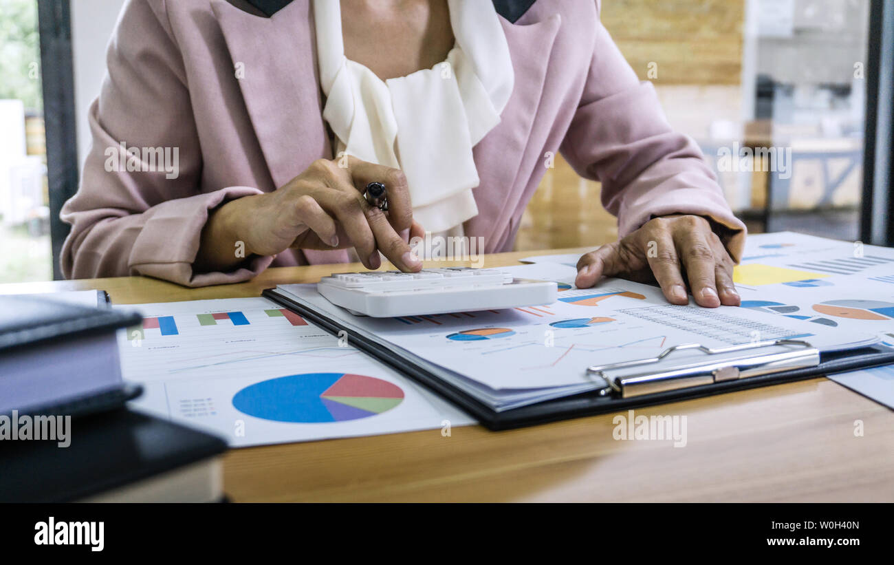 Business donna contabile che lavora e calcolando i dati finanziari sul grafico documenti, facendo finanziare in workstation. Foto Stock