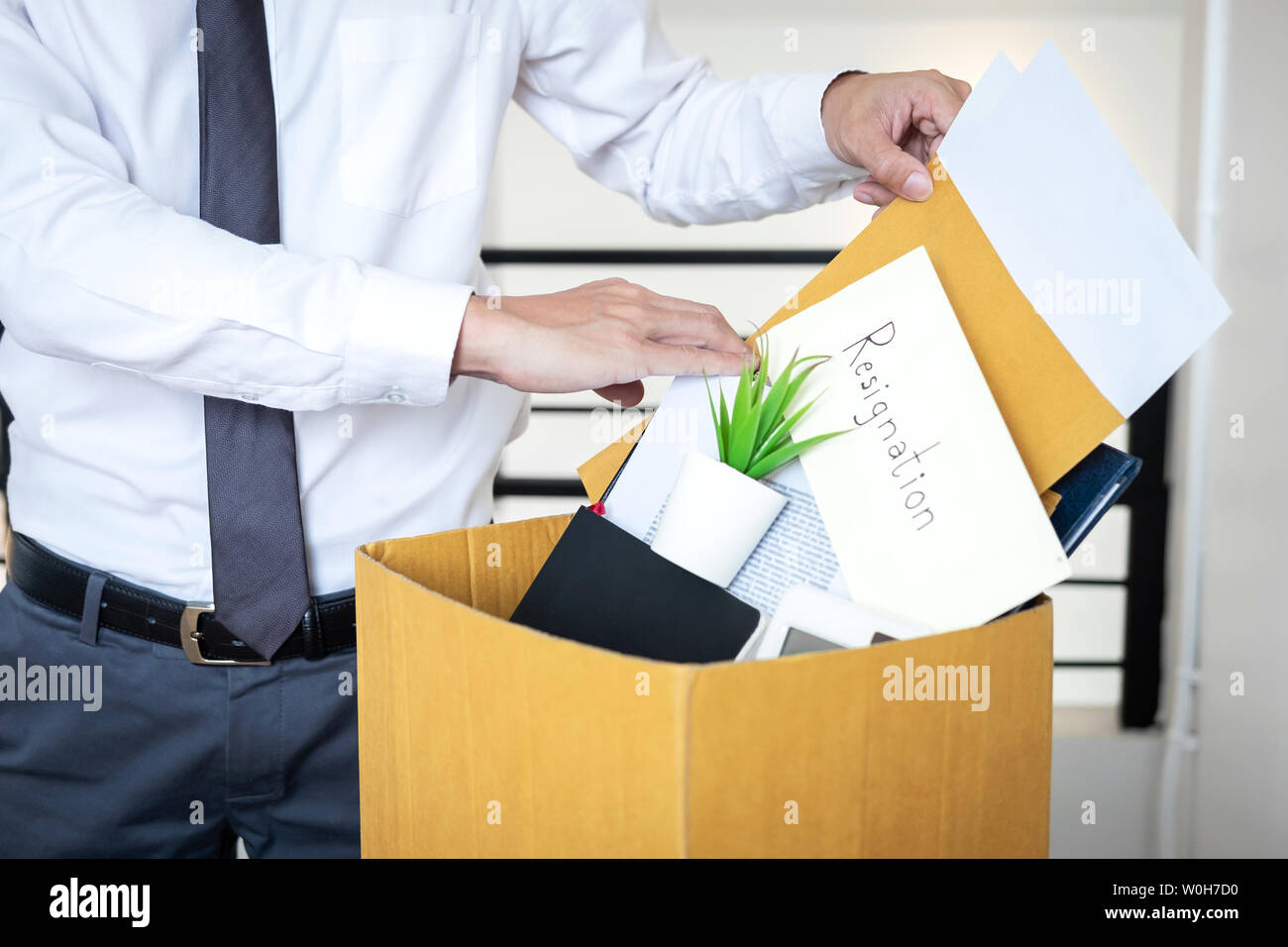 Imprenditore inviando una lettera si essendo di rassegnazione e di trasportare beni di imballaggio azienda e file in marrone scatola di cartone, modifica e dimissionario f Foto Stock