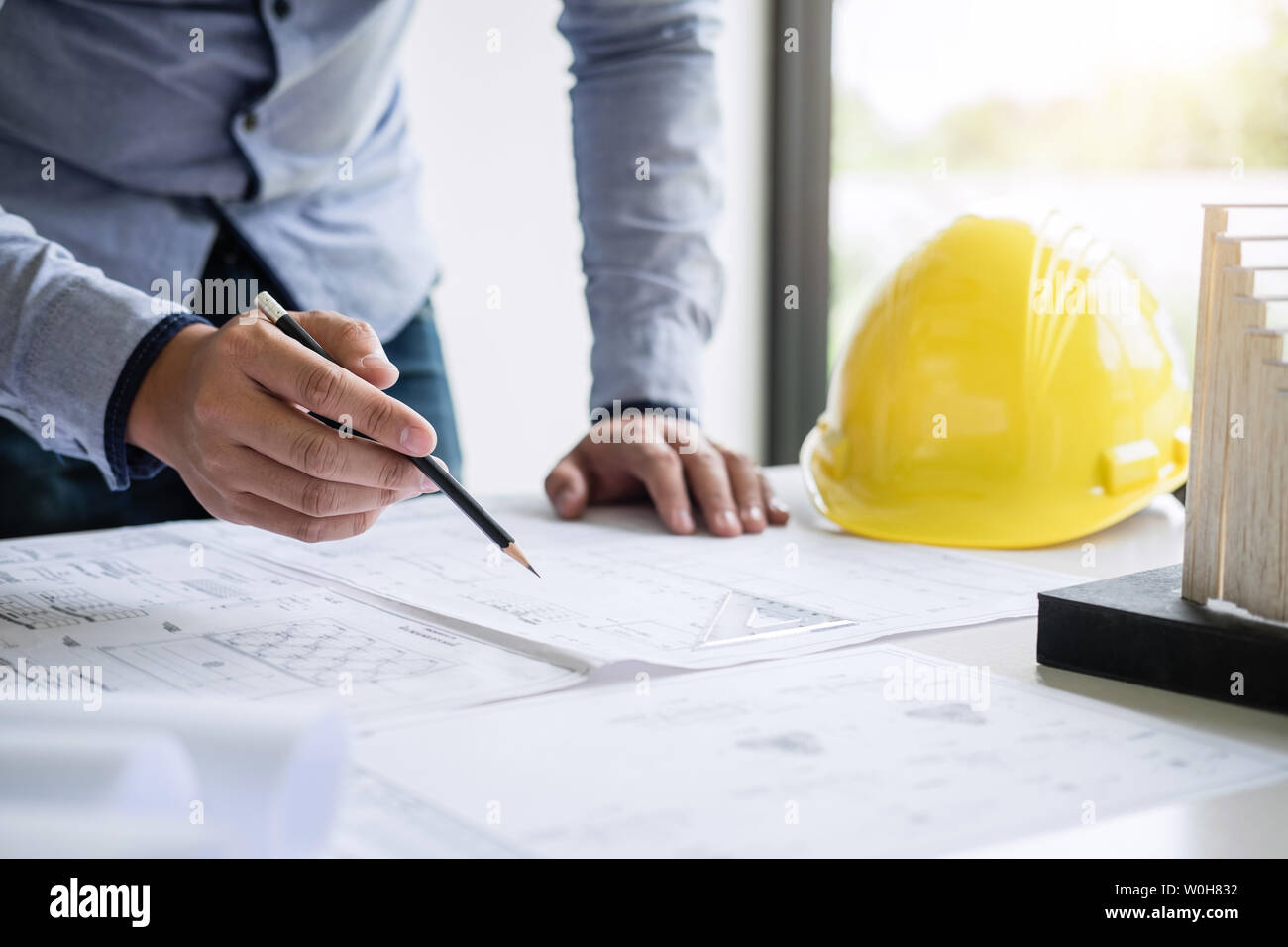 Ingegneria edile o architetto mani lavorando su blueprint ispezione nei luoghi di lavoro, mentre la verifica delle informazioni disegno e schizzi per archita Foto Stock