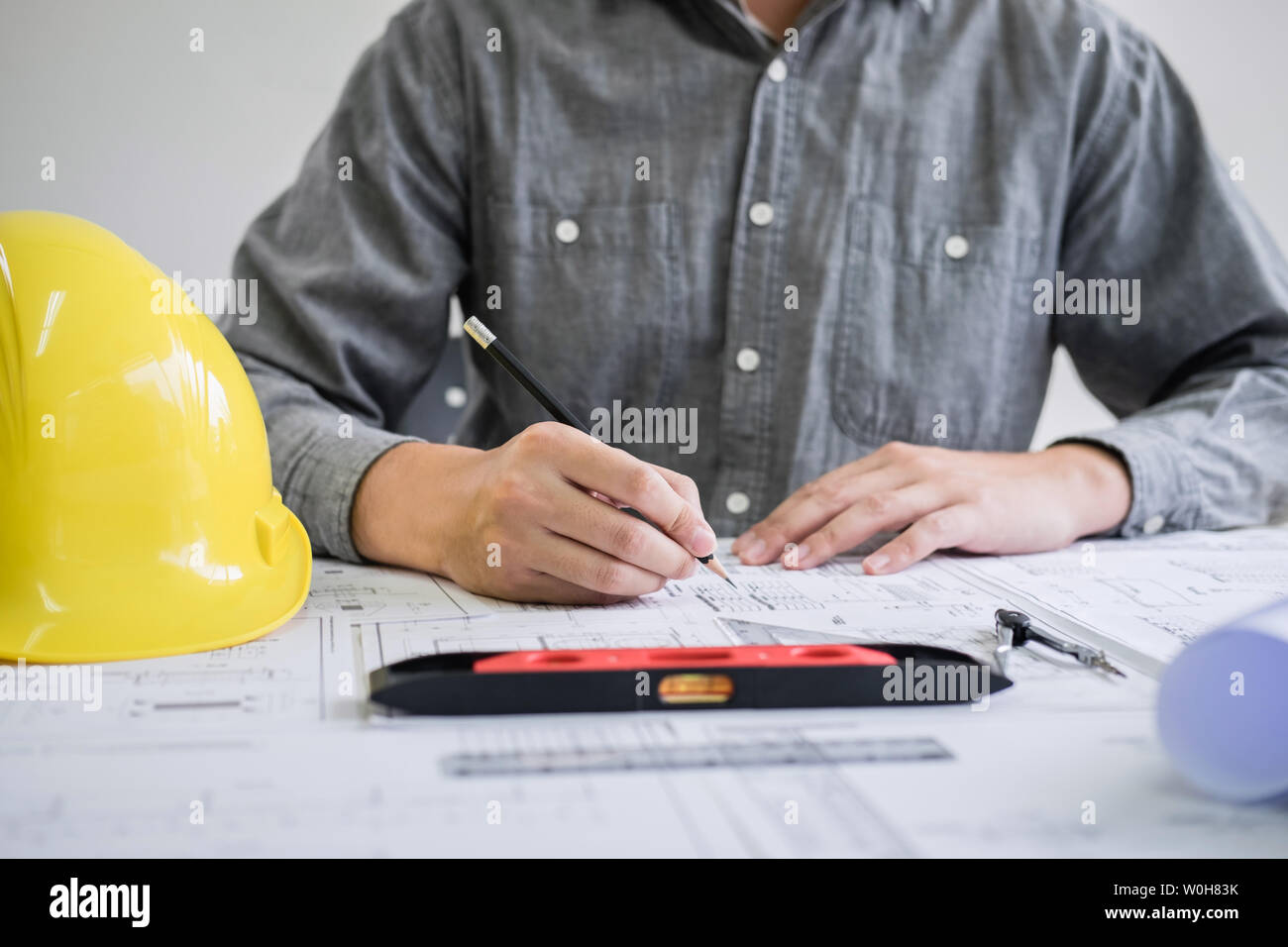 Ingegneria edile o architetto mani lavorando su blueprint ispezione nei luoghi di lavoro, mentre la verifica delle informazioni disegno e schizzi per archita Foto Stock