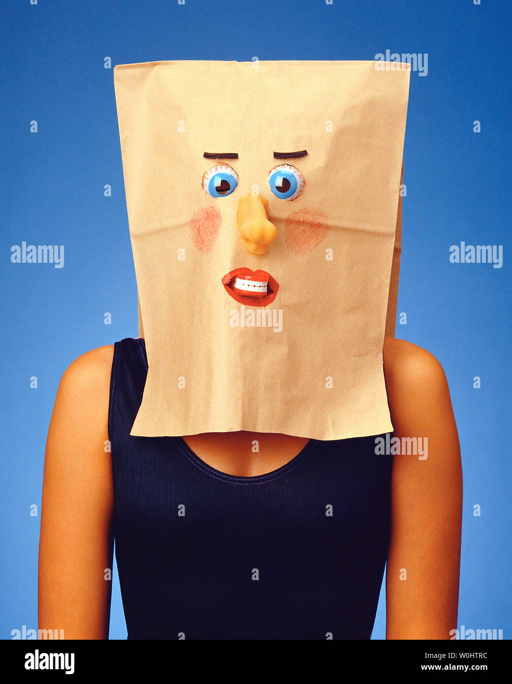Donna con una carta shopping bag sopra la sua testa che è decorato con una faccia Foto Stock