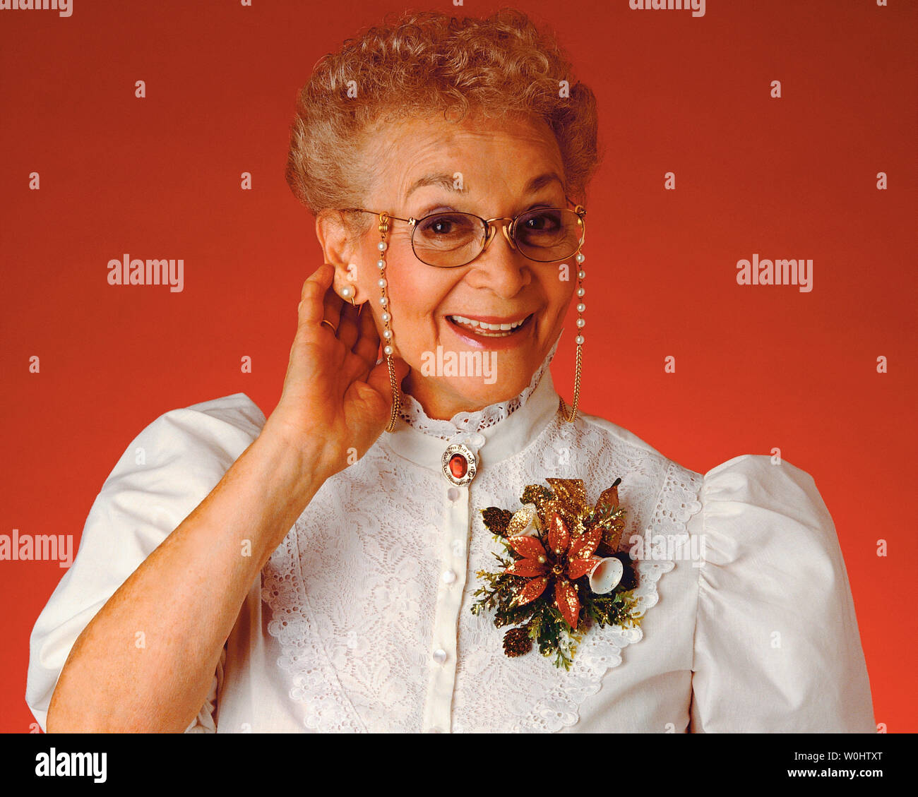 Senior donna che indossa un corpetto vestita di bianco con gli occhiali Foto Stock