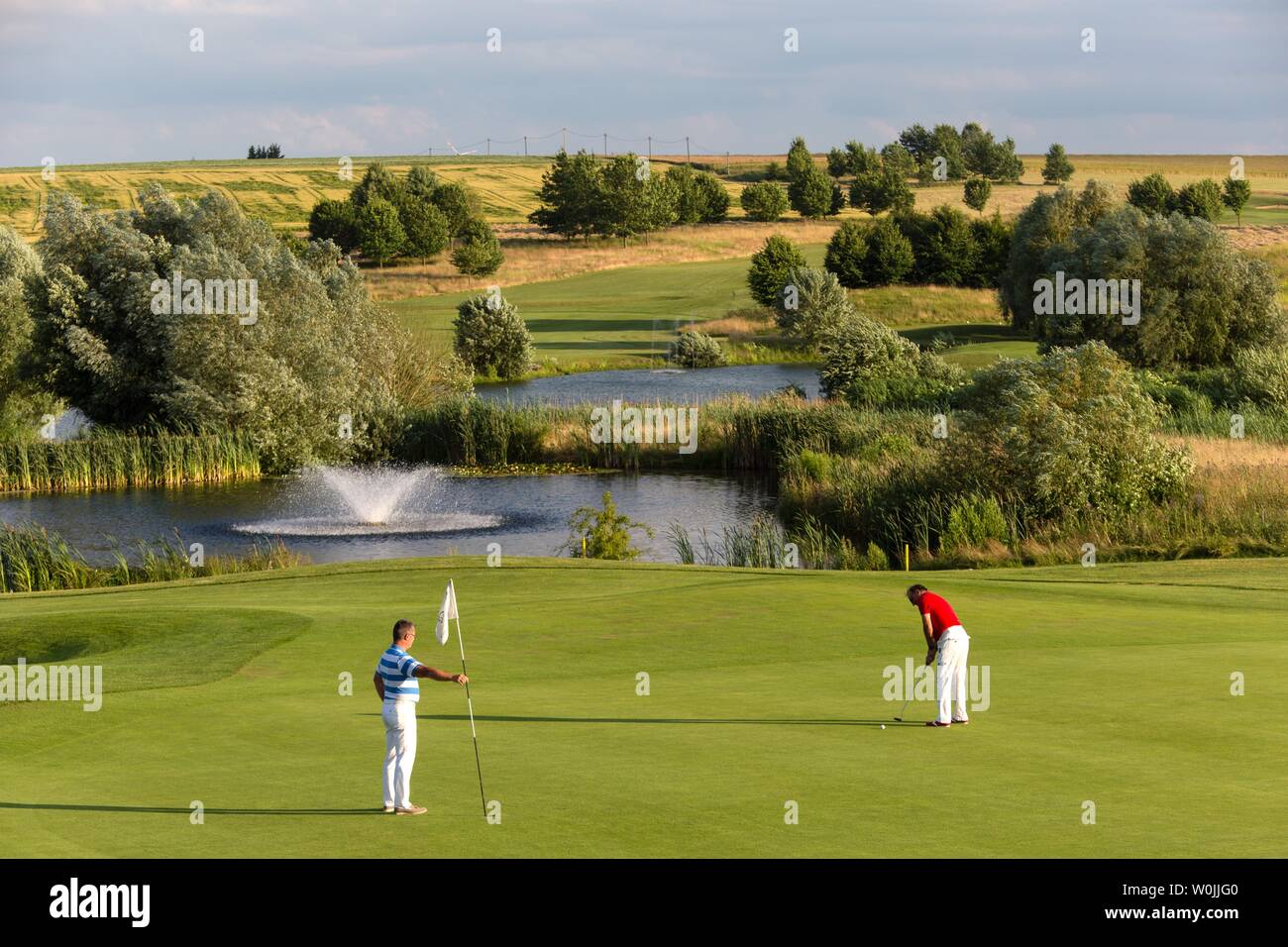 Giocatore di golf putt, il campo da golf con acqua ostacolo, Markt Indersdorf, Alta Baviera, Baviera, Germania Foto Stock