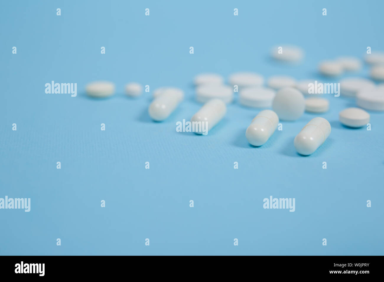 Bianco pillole mediche su sfondo blu con una copia dello spazio Foto Stock