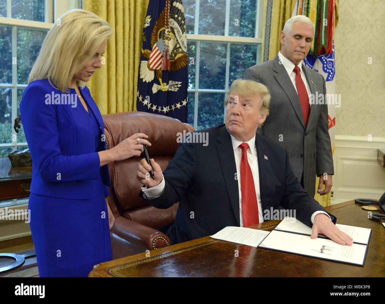 Presidente Donald Trump mani la penna utilizzata per firmare un ordine esecutivo che ferma la separazione delle famiglie di immigrazione al DHS Segretario Kirstjen Nielsen come Vice Presidente Mike Pence assiste in ufficio Ovale della Casa Bianca, Giugno 20, 2018 a Washington, DC. Trump invertita una politica dopo una protesta dei bambini sono stati presi dalle famiglie che cercano di attraversare il confine messicano in Texas. Foto di Mike Theiler/UPI Foto Stock