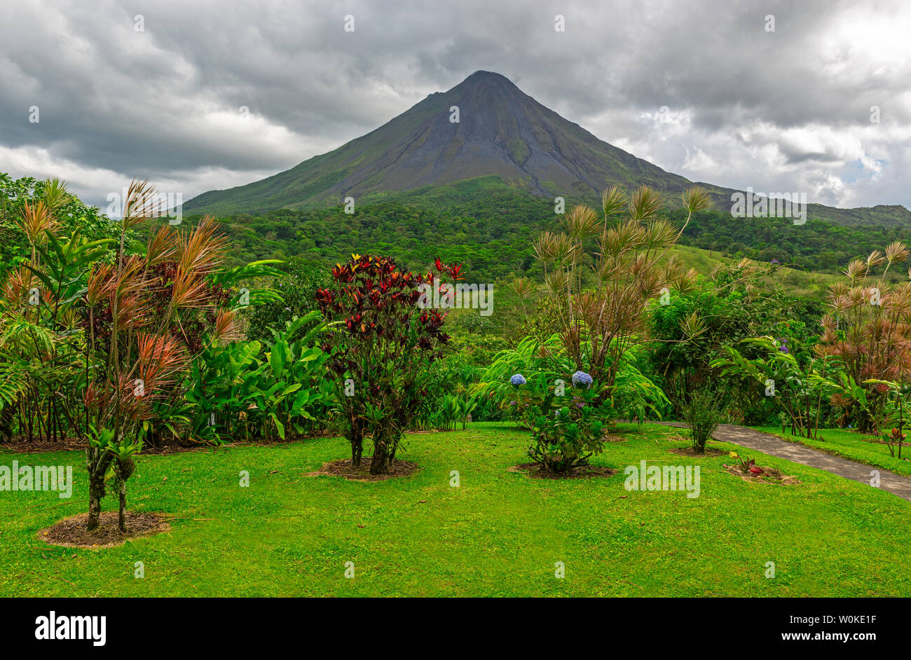 Il maestoso vulcano Arenal con un cielo drammatico e di un giardino ornamentale, La Fortuna, Costa Rica, l'America centrale. Foto Stock