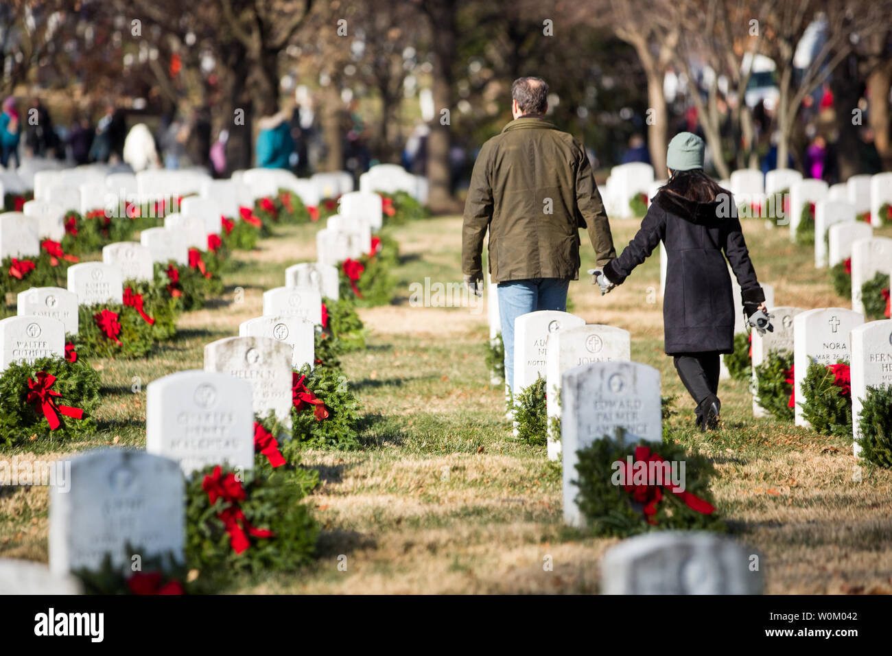 Volontari tenere le mani a piedi attraverso il Cimitero Nazionale di Arlington dopo il posizionamento delle corone di fiori sulle lapidi come parte dell'annuale "ghirlande in tutta l'America' evento in Arlington, VA sul dicembre 16, 2017. La manifestazione si svolge a livello nazionale e lo stato i veterani dei cimiteri in tutto il paese. Foto di Erin Schaff/UPI Foto Stock