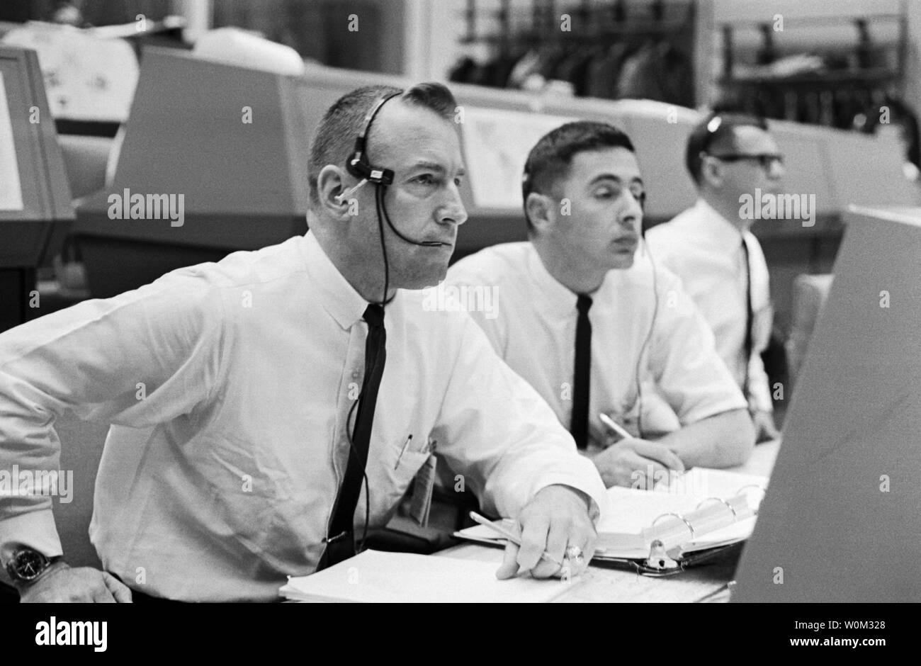 Astronauta Jim Lovell (in primo piano), che serve come Houston CAPCOM (capsula Communicator), orologi il lancio di Gemini 8 al Johnson Space Center a Houston, Texas, il 16 marzo 1966. Marzo 16, 2016 è il cinquantesimo anniversario della NASA Gemini 8 missione la sesta voli spaziali con equipaggio condotto durante gli Stati Uniti' Progetto Gemini programma. L'obiettivo primario della missione, il docking di successo di due veicoli spaziali in orbita, un primo volo spaziale, è stato un successo anche se l'equipaggio dovrebbe sperimentare una critica in-space system failure, costringendoli ad abbandonare la missione prematuramente. UPI Foto Stock