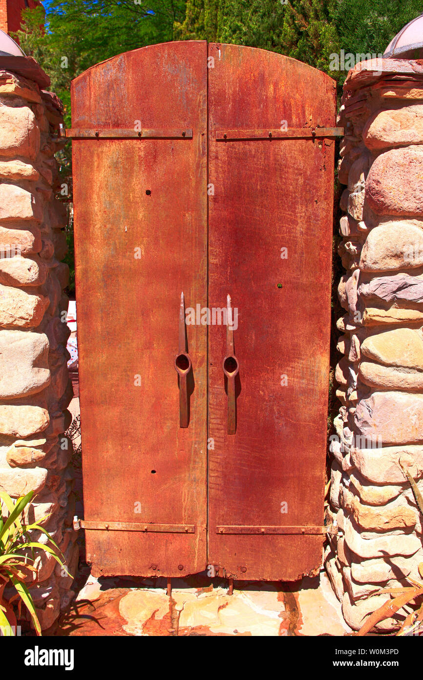 Due metallo arrugginito porte con pick-ax capi per maniglie che conduce al cortile ristorante birreria su Ave nel centro cittadino di Bisbee, AZ Foto Stock