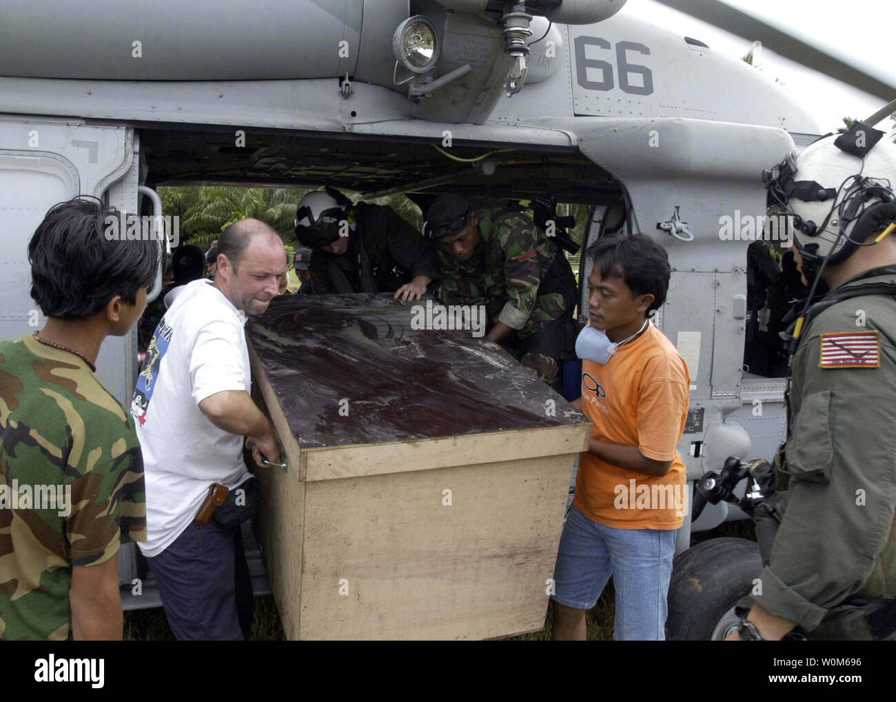 Gli operatori umanitari stranieri e militari lavorano insieme per scaricare una scatola di tsunami di forniture di soccorso a Sumatra, Indonesia, da un MH-60S Knighthawk elicottero assegnato al 'Gunbearers' di elicottero di lottare contro lo squadrone di supporto undici (HC-11) a Gennaio 10, 2005. (UPI Photo/ Patrick M. Bonafede/Navy US) Foto Stock