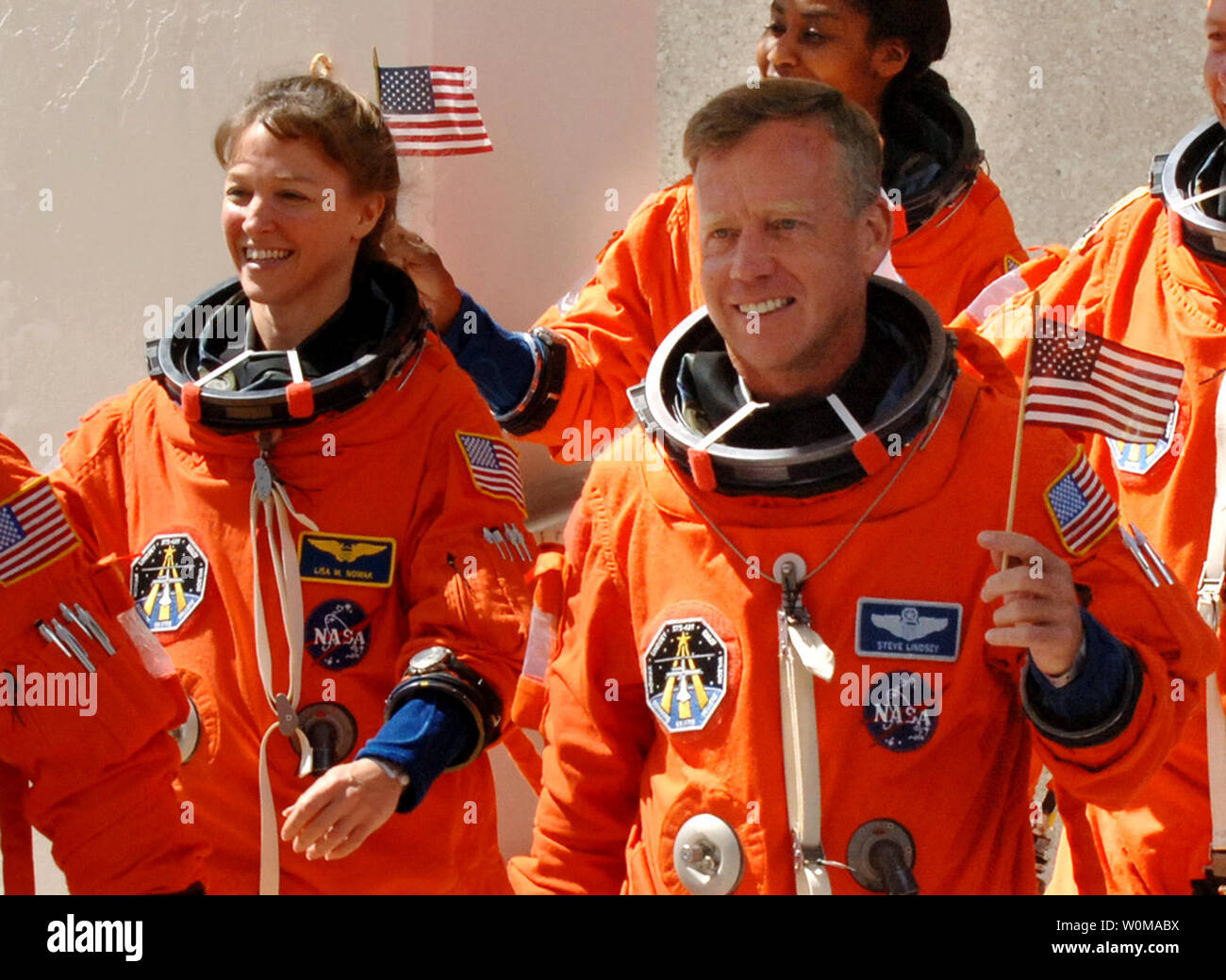 Astronauta Lisa Nowak (L) è stato caricato con il tentato omicidio di primo grado e il 6 febbraio 2007. La polizia dice che Nowak ha spinto 900 miglia e indossato un travestimento prima di fronte a una donna che ha creduto era un concorrente per le affezioni del Navy Cmdr. William Oefelein, un celibe compagno astronauta. Nowak è mostrato sventola una bandiera americana come ha camminato fuori delle operazioni e Checkout edificio con colleghi astronauti a bordo della NASA Astrovan in rotta per la navetta spaziale Discovery per la missione STS-121 a Cape Canaveral, in Florida il 4 luglio 2006. A destra è il comandante Steve Lindsey. (UPI foto/Pat B Foto Stock