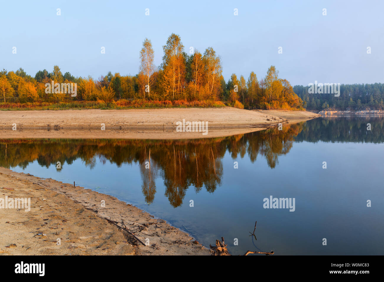 Caduta di alberi colorati su una riva di un fiume con riflessi nell'acqua Foto Stock
