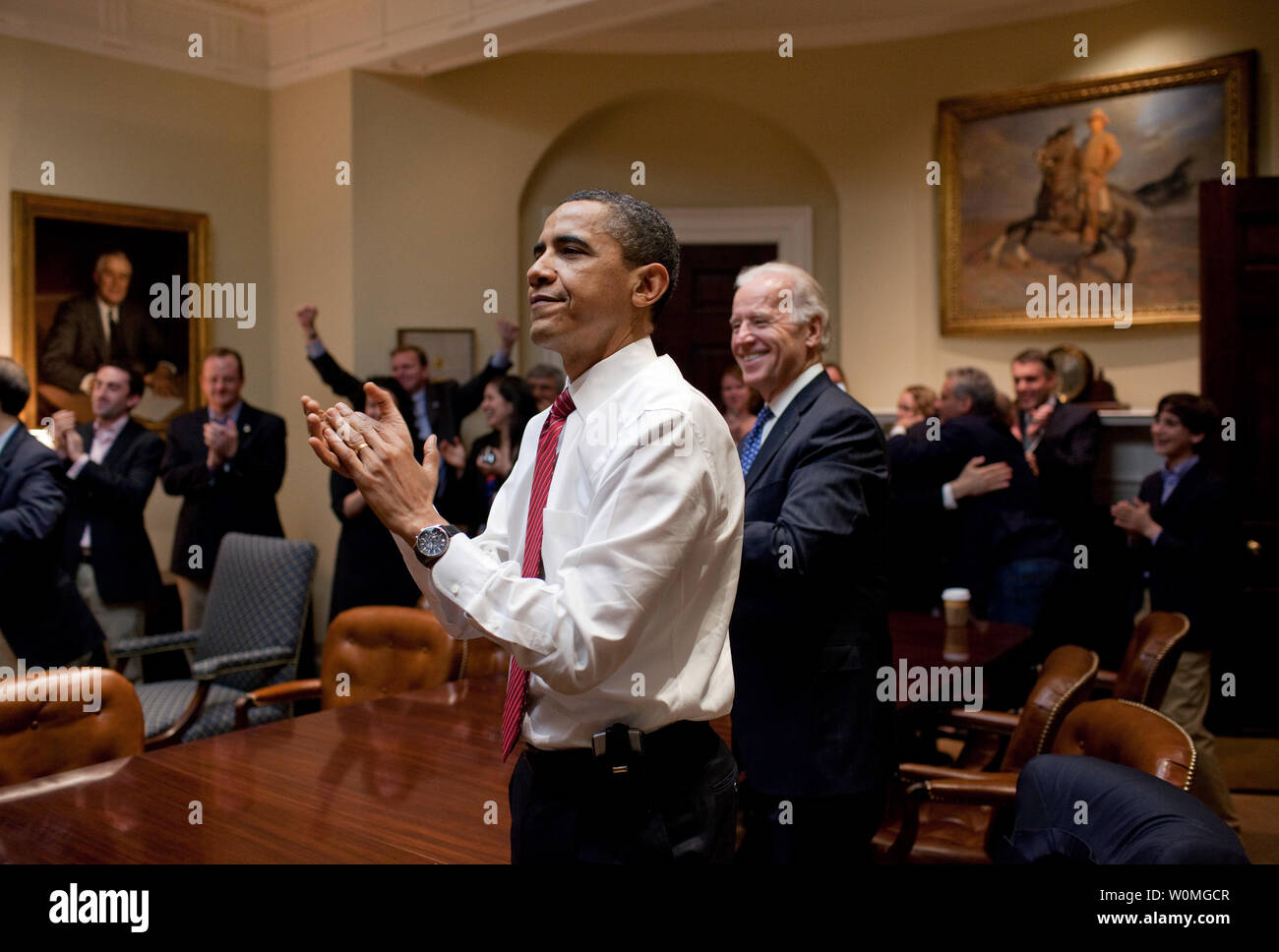 Stati Uniti Barack Obama presidente, vice presidente Joe Biden e senior staff applaudire nella sala Roosevelt della Casa Bianca come la casa passa il della riforma sanitaria bill, fine il 21 marzo 2010. A sinistra si trova un dipinto del Presidente Franklin D. Roosevelt e a destra è il presidente Teddy Roosevelt. UPI/Pete Souza/White House Foto Stock