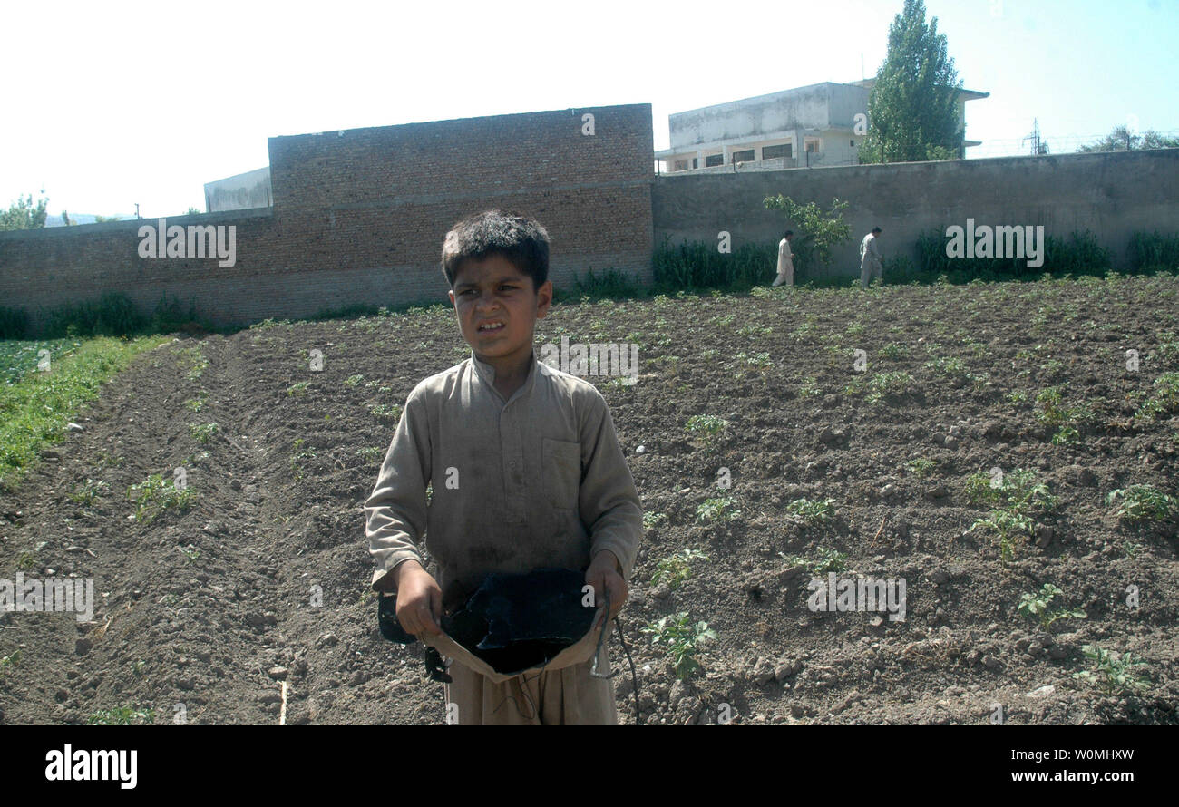 Un ragazzo tiene un pezzo di metallo carbonizzato accanto a milioni di dollari di composto in cui al-Qaida chief Osama bin Laden era nascosto in Abbottabad, in Pakistan il 3 maggio 2011. Osama bin Laden è stato ucciso dalle forze speciali degli Stati Uniti, in un firefight su Maggio 1, 2011. UPI/Sajjad Ali Qureshi Foto Stock