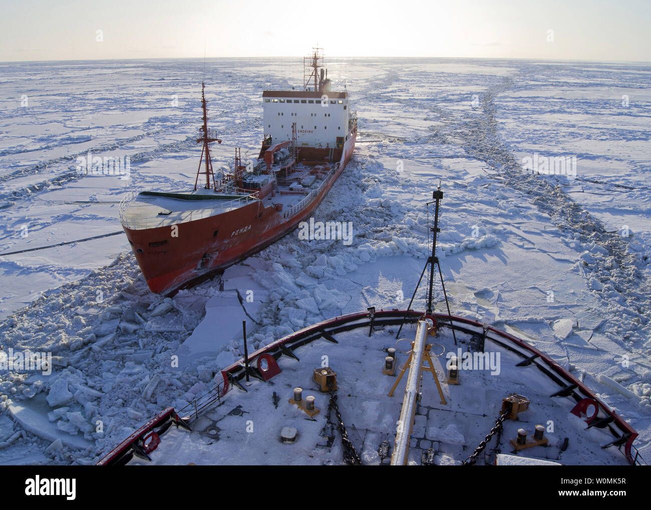 La petroliera russa renda siede nel ghiaccio come NEGLI STATI UNITI Guardacoste Healy rompe il ghiaccio circa 250 miglia a sud di nome, Alaska nel mare di Bering su Gennaio 6, 2012. Le navi sono in transito attraverso il ghiaccio fino a cinque metri di spessore in questa zona. La petroliera renda sta portando 1.3 milioni di galloni di carburante per il nome, come la città non ha ricevuto il suo ultimo invernali pre-imbarco a causa di tempeste. UPI/STATI UNITI Coast Guard Foto Stock