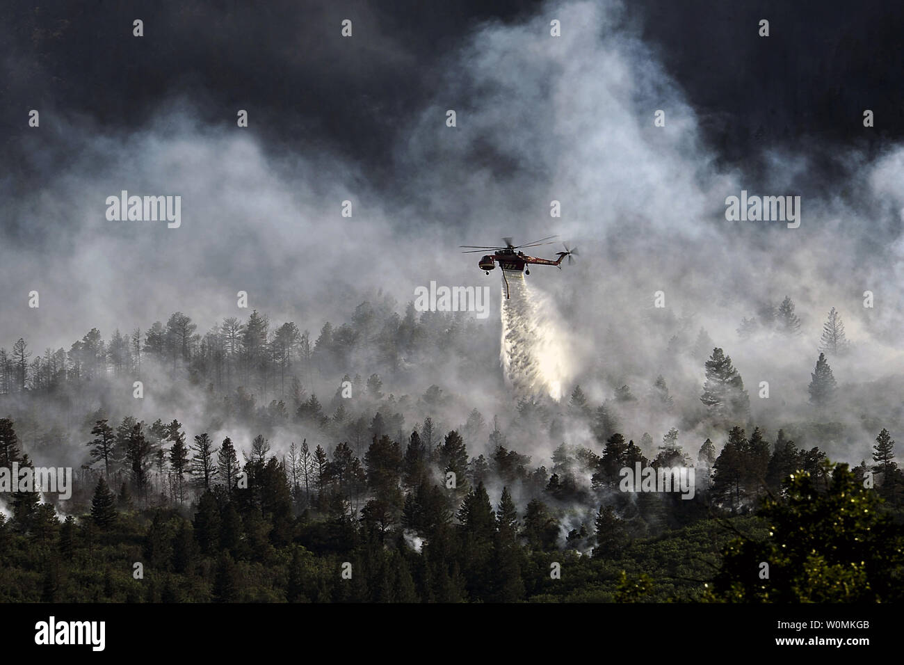 Un elicottero scende acqua sul fuoco come i vigili del fuoco hanno continuato a combattere il blaze che ardeva nelle ore serali in Waldo Canyon per gli Stati Uniti Air Force Academy, 27 giugno 2012. Gli incendi che hanno bruciato oltre 15.000 acri, iniziò a diffondere all'angolo sudoccidentale dell'Accademia nella mattina in anticipo, facendo in modo che i funzionari di base per evacuare i residenti. Funzionari ha stimato che il fuoco si era diffuso in circa dieci ettari di terreno appartenente all'Accademia. Attualmente più di 90 vigili del fuoco da Accademia, lungo con beni dalla Air Force Space Command; F.E. Warren Air Force Base, Wyoming; Fort Foto Stock