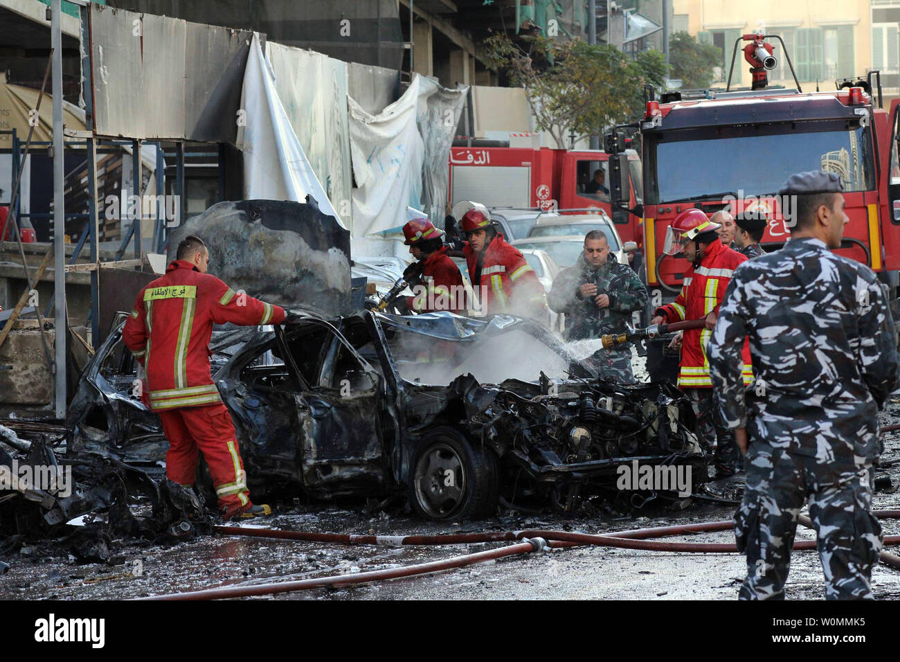 Fire e dei funzionari di polizia si riuniranno presso il sito di un'esplosione nel centro cittadino di Beirut che ha ucciso almeno cinque persone, inclusi gli ex ministro libanese Mohamad Chatah, il 27 dicembre 2013. Chatah, chi è un accanito oppositore del Presidente siriano Bashar al-Assad, è stato ucciso in una massiccia esplosione che mirate il suo convoglio di auto. Più che 70 persone sono rimaste ferite. UPI/Mohamad Sultan Foto Stock