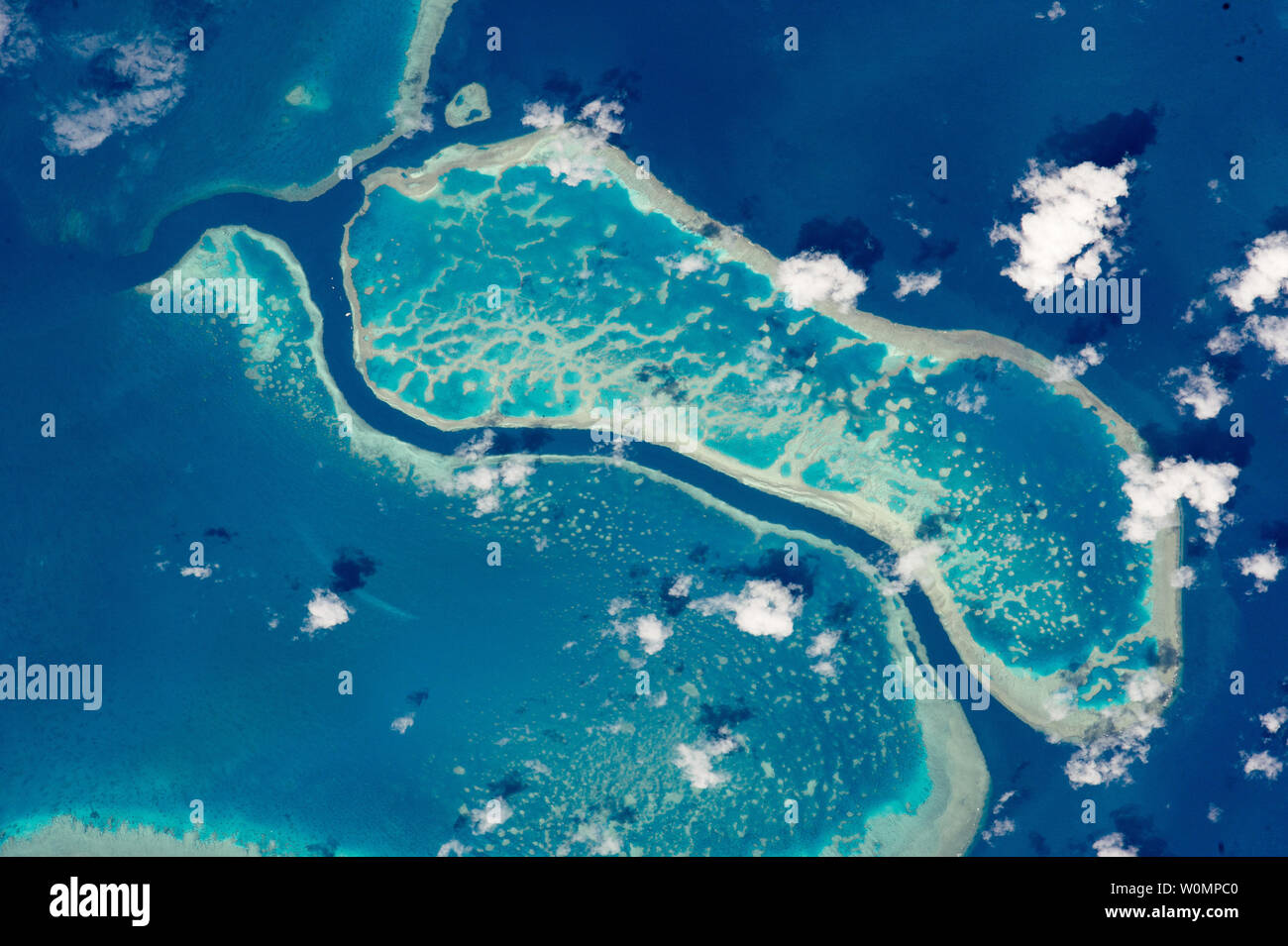 Un astronauta a bordo della Stazione Spaziale Internazionale catturato una vista di questi tre scogli in Australia la Grande Barriera Corallina su ottobre 12, 2015. L'area di foto si estende per circa dieci miglia di 1.700 miglia sistema di barriera corallina. Le scogliere sono facili da individuare dalla spazio poiché l'iridato blues di lagune forte contrasto con il blu scuro delle acque profonde. La Grande Barriera Corallina è il più grande sistema corallino sulla terra, con più di 3 mila barriere separate e formazioni coralline. È anche uno dei più complessi ecosistemi naturali, con 600 tipi di coralli e migliaia di specie animali da minuscoli planktons balene. Foto Stock
