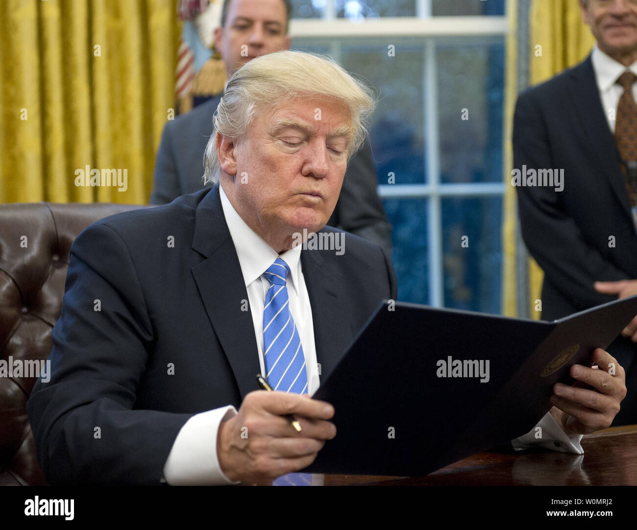 Il Presidente degli Stati Uniti, Donald Trump legge il primo dei tre ordini esecutivi firmerà nell'Ufficio Ovale della Casa Bianca di Washington il 23 gennaio 2017. Questo uno riguardava il ritiro degli Stati Uniti dal partenariato Trans-Pacific (TPP). Gli altri sarà un governo USA congelamento delle assunzioni per tutti i reparti ma il militare, e "Messico City' che vieta il finanziamento federale di aborti all'estero. Foto Stock