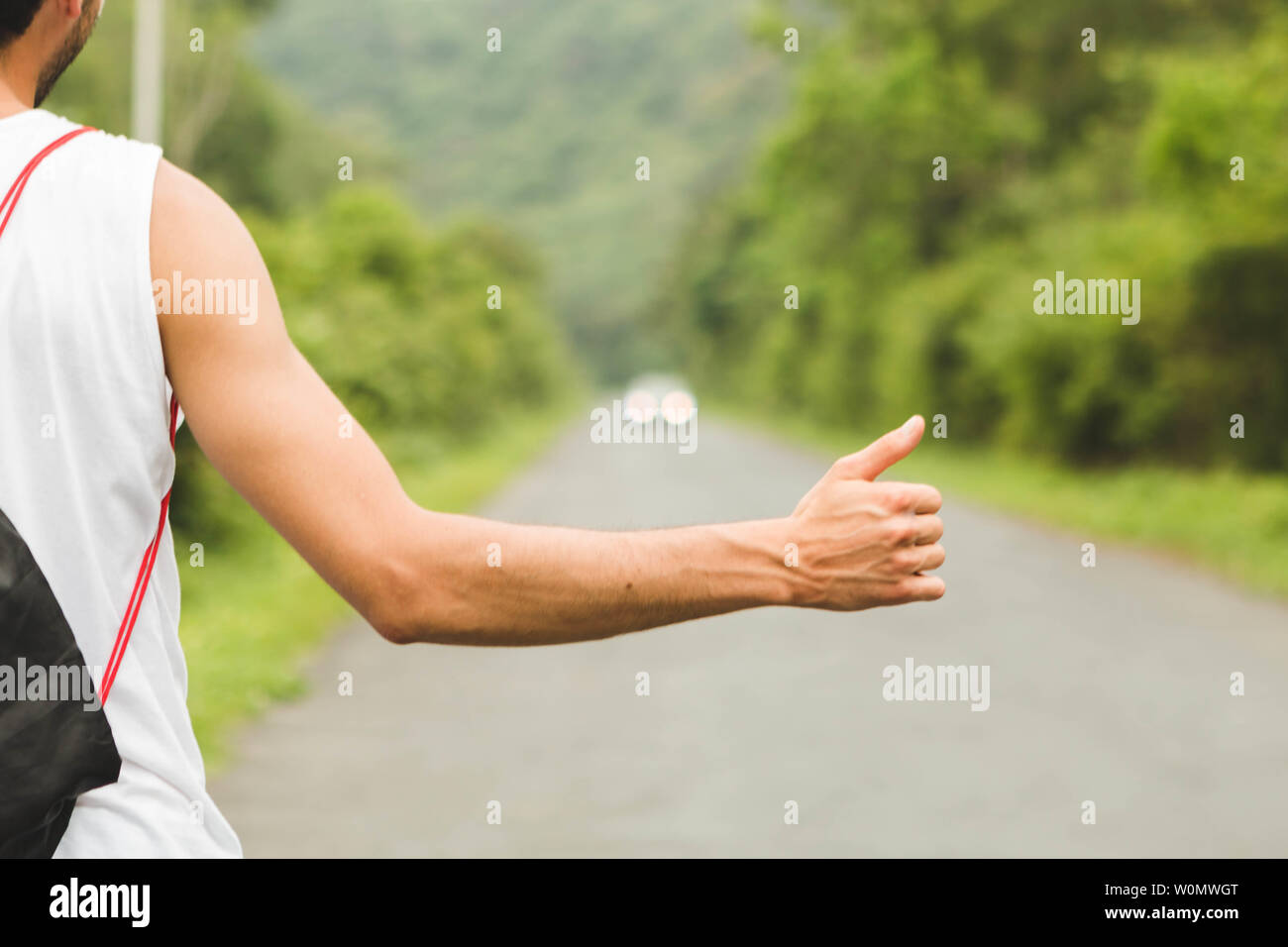 Chiudere i giovani il braccio e la mano autostop sulla strada di montagna. Foto Stock