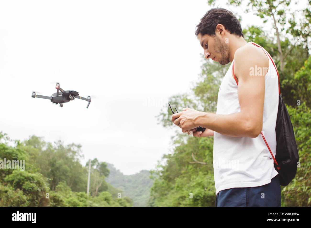 Vista laterale di un giovane ragazzo di imparare a volare un drone in all'aperto Foto Stock