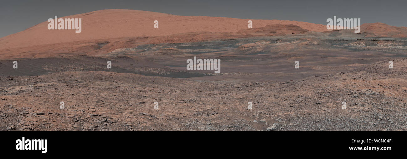 Questo mosaico, preso dalla curiosità di Mars rover su Sol 1931 nel gennaio 2018, guarda in salita al Monte Sharp. Spanning il centro dell'immagine è una zona con clay-cuscinetto rocce che gli scienziati sono ansiosi di esplorare; esso potrebbe chiarire la luce aggiuntiva sul ruolo dell'acqua nel creare il paesaggio. Il mosaico è stato assemblato da decine di immagini prese dalla curiosità montante della fotocamera (Mastcam). Montare forte si erge nel mezzo di Gale cratere, che è 96 miglia di diametro. Questo tumulo che la curiosità è stata scalata dal 2014, probabilmente formato in presenza di acqua a vari punti di tempo in Mars' antica Foto Stock