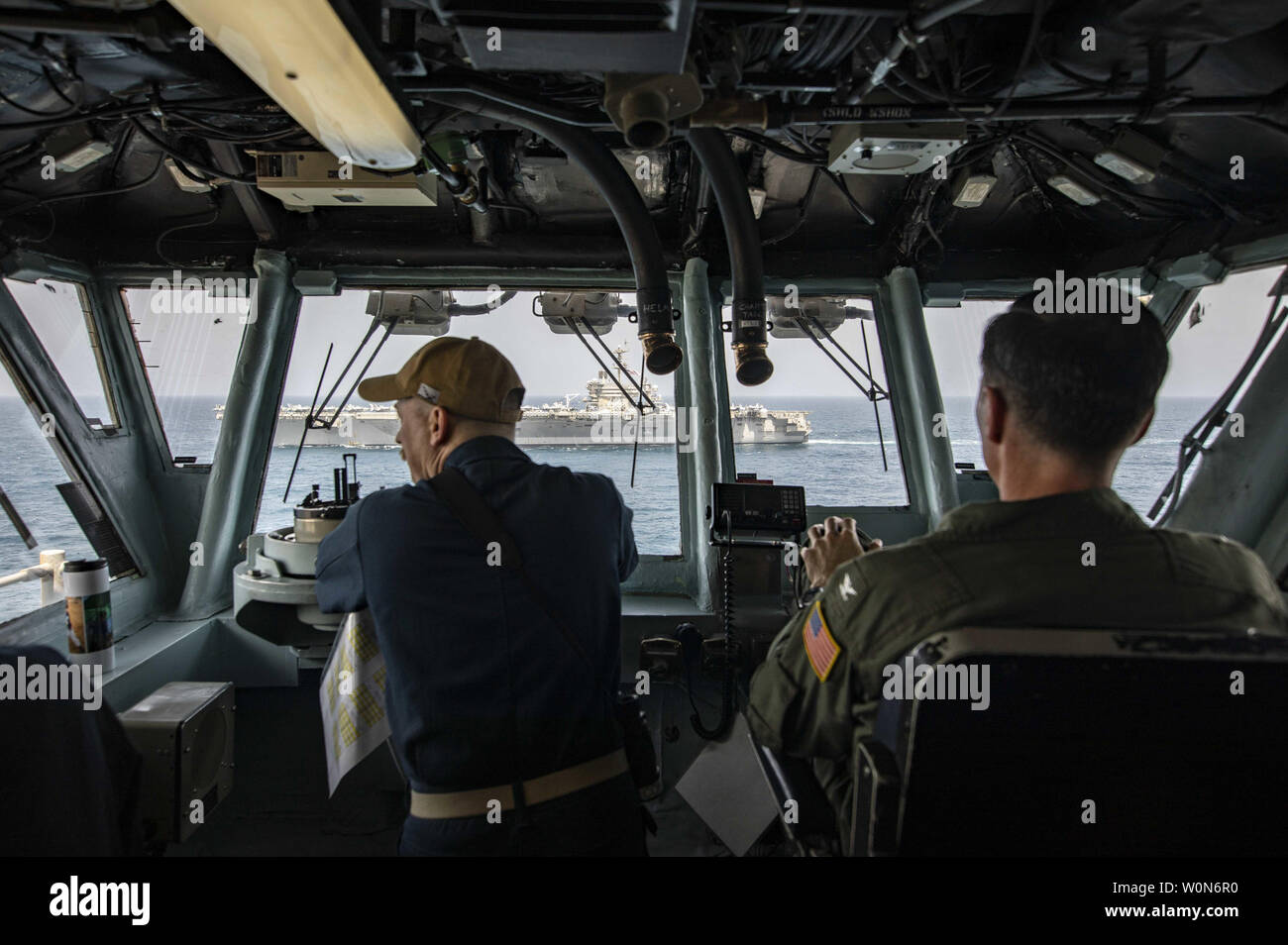 Il cap. Jason Rimmer, destra, comandante della Wasp-classe assalto anfibio nave USS Kearsarge (LHD 3), alfiere di Justin Mays sta guardare in Kearsarge il pilota di casa come la Nimitz-class portaerei USS Abraham Lincoln (CVN 72) cuoce a vapore mediante il 17 maggio 2019. La Abraham Lincoln Carrier Strike gruppo (ABECSG) e Kearsarge Amphibious Ready Group (KSGARG) stanno conducendo operazioni congiunte negli Stati Uniti Quinta Flotta area di operazioni. Il ABECSG e KSGARG, con l'avviato 22 Marine Expeditionary Unit, sono preparati per rispondere alle emergenze e di difendere le forze degli Stati Uniti e degli interessi nel re Foto Stock