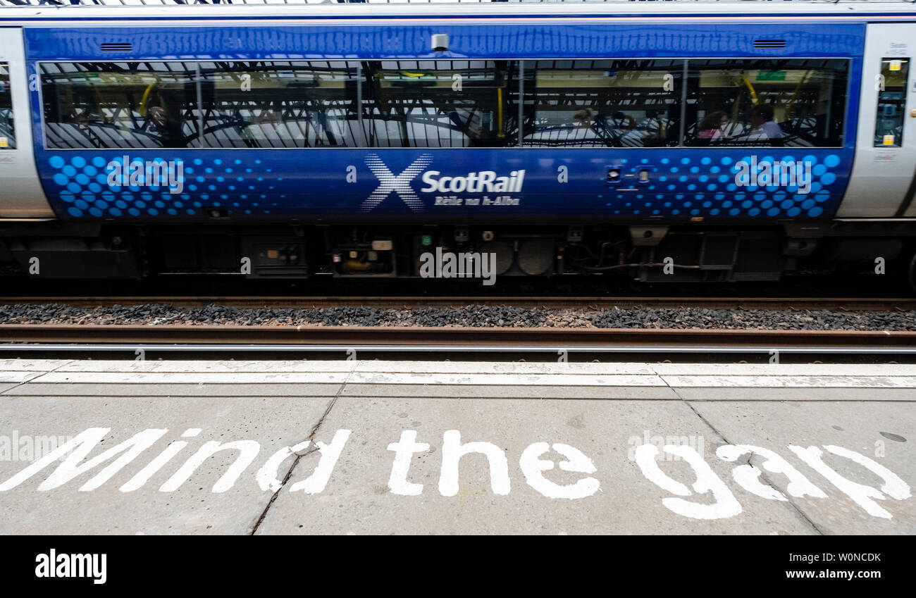 Vista della Scotrail treni passeggeri alla stazione della piattaforma con la mente lo spazio dipinto di avvertimento sul bordo, Stirling, Scozia, Regno Unito Foto Stock
