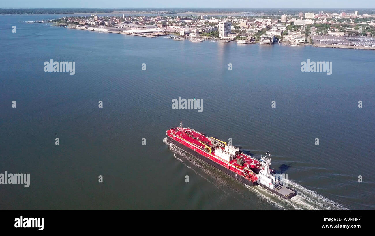 Vista aerea di barge in movimento attraverso il porto di Charleston con il porto e il centro cittadino di Charleston in background. Foto Stock