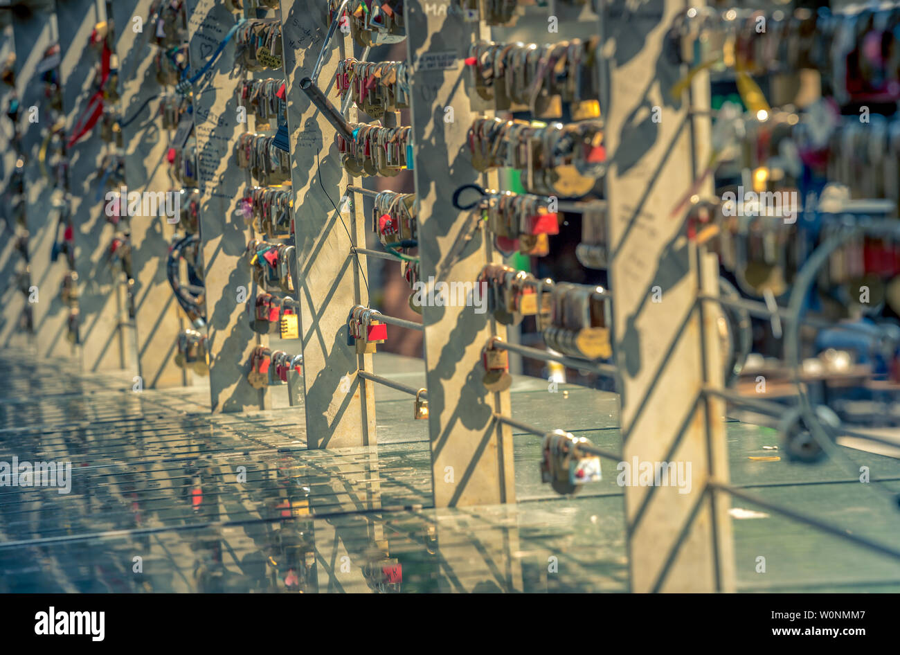 Serrature con un cuore e un sacco di altre serrature sul ponte con la riflessione. segno di amore eterno. Foto Stock