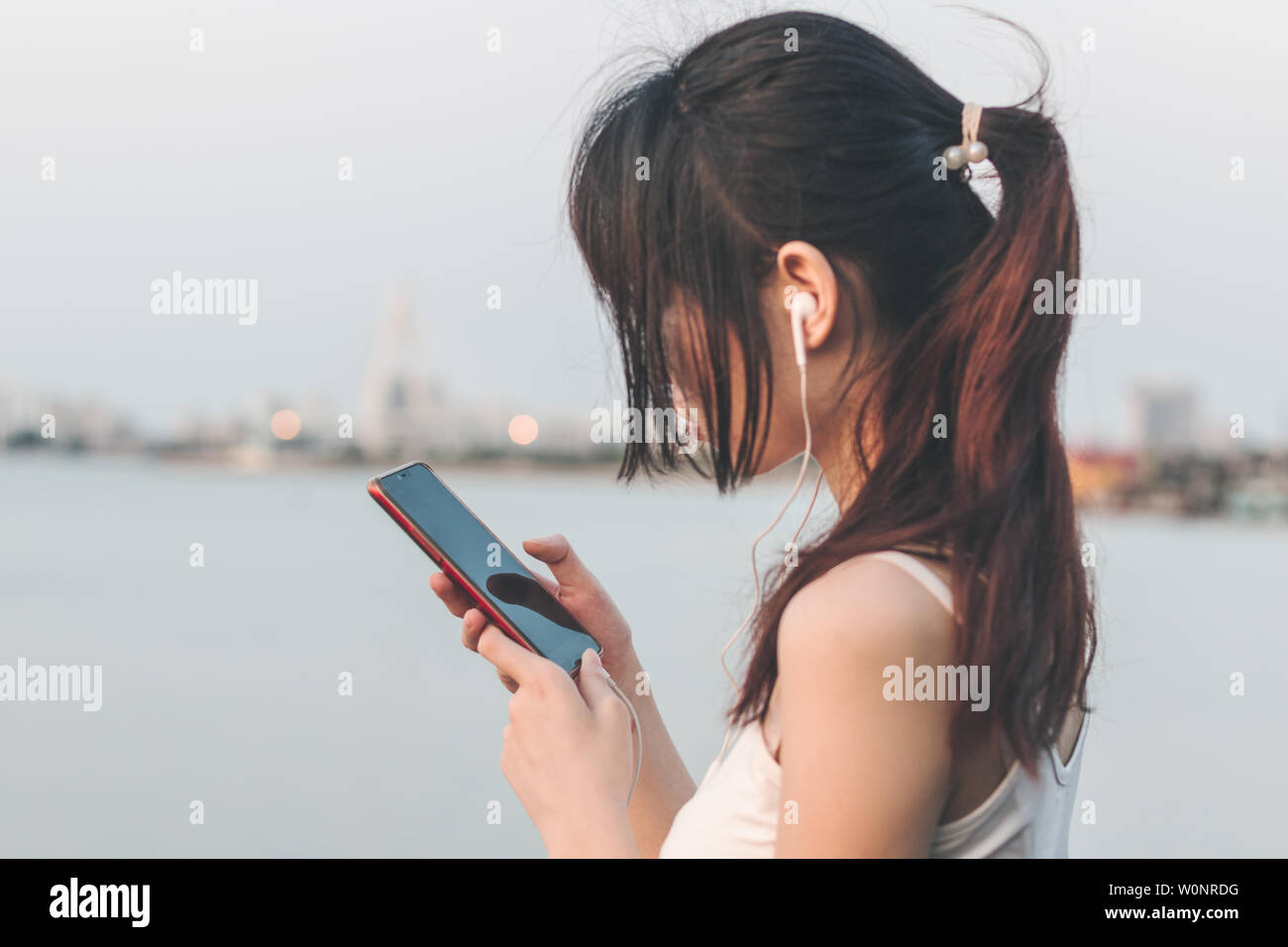 Una ragazza di ascolto di musica dal mare. Foto Stock