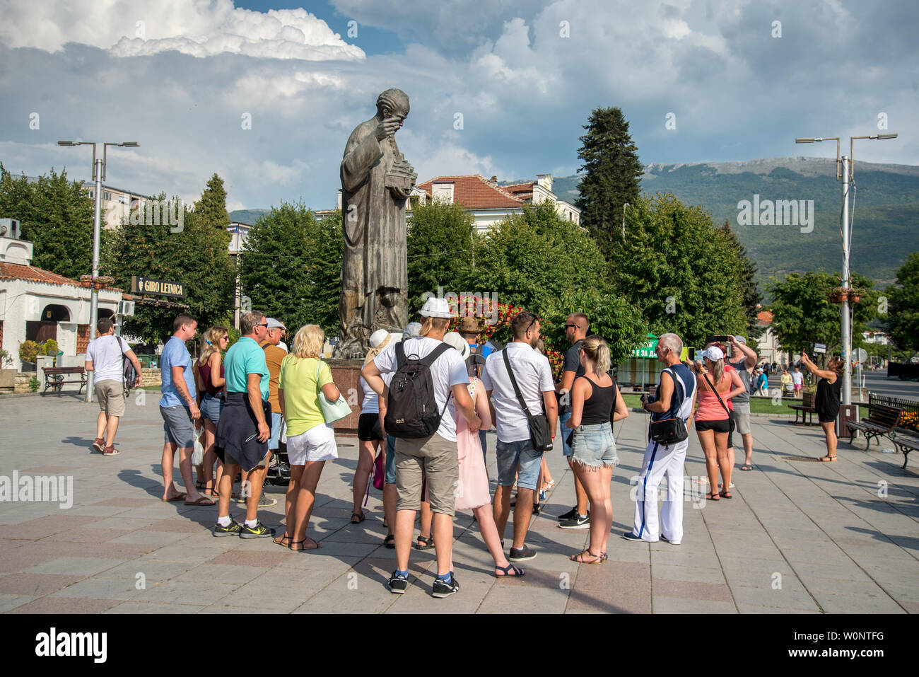 Guidate il gruppo turistico si raccoglie attorno la statua di San Clemente ,vicino al porto e il lago.che fondò il monastero di San Clemente a Ohrid Foto Stock