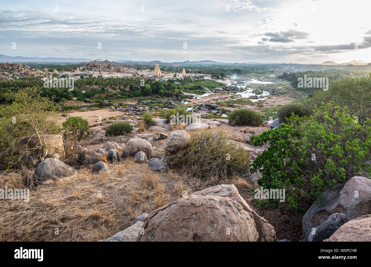 Una vista di Hampi con i suoi templi, fiumi e campi di riso, al tramonto. Foto Stock