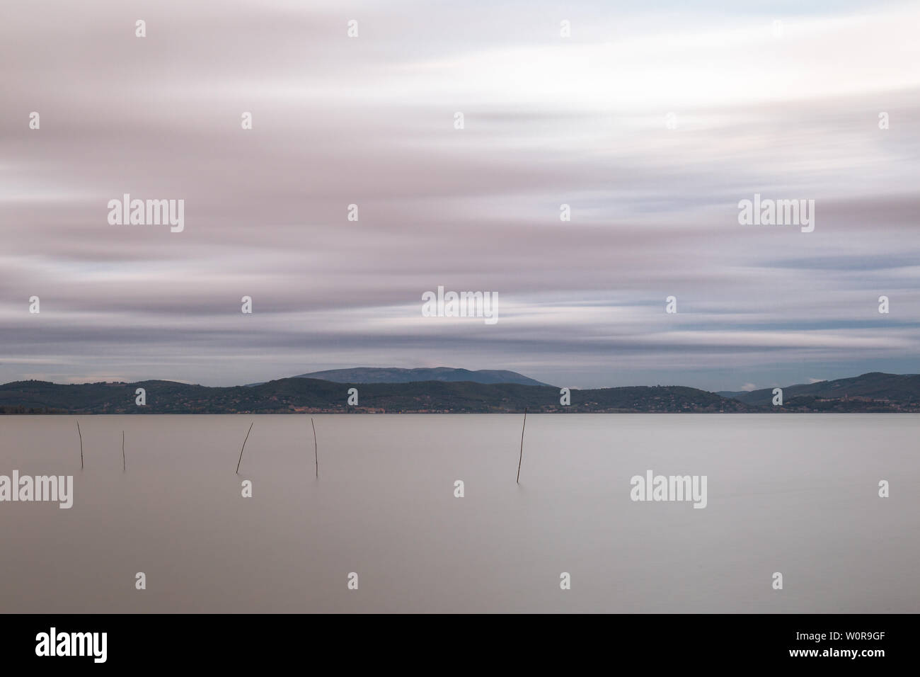 Bella lunga esposizione vista del lago Trasimeno (Umbria, Italia), ancora con acqua e nuvole in movimento Foto Stock