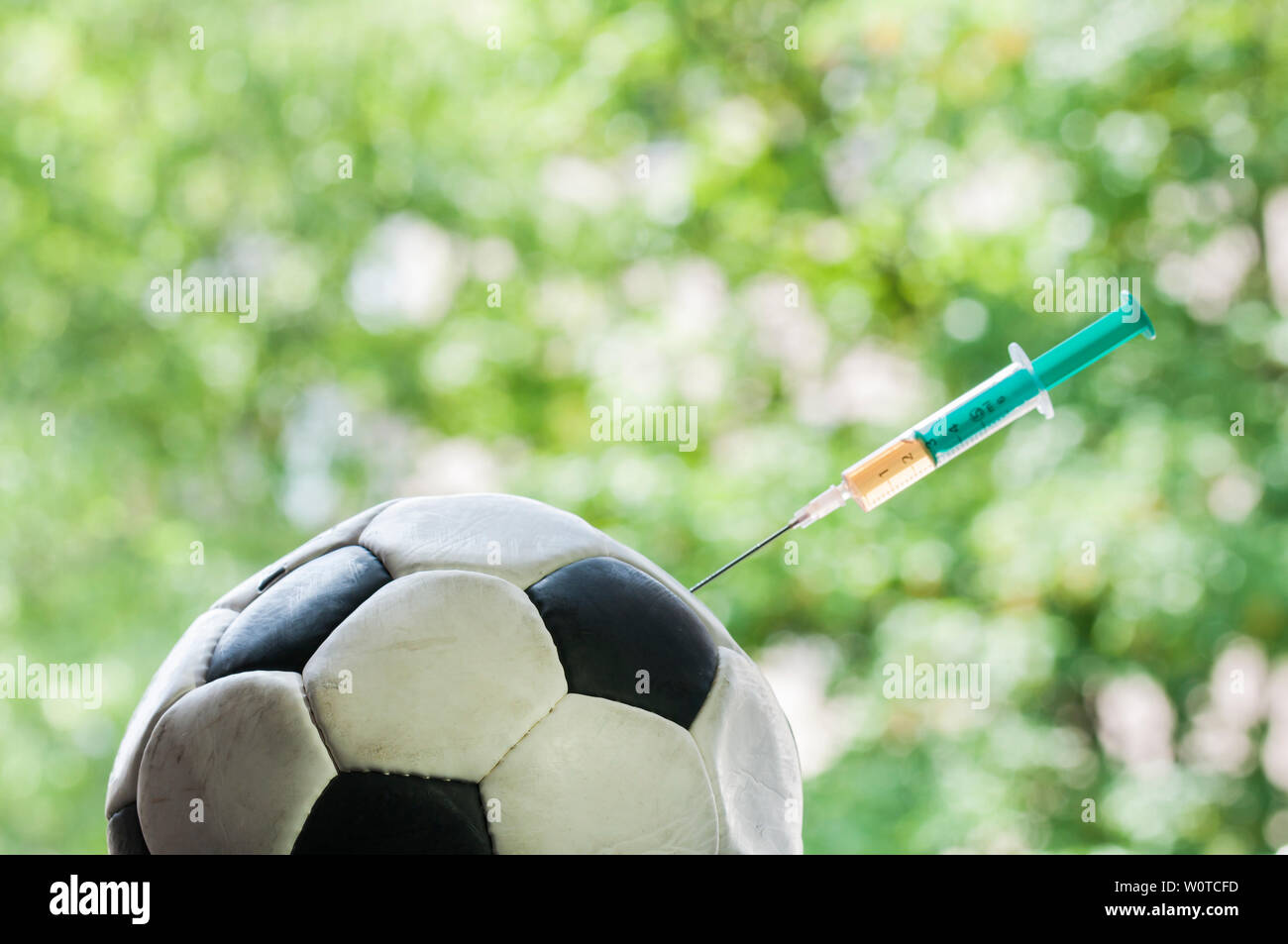 Ein Fussball bekommt eine Injektion mit einer Spritze, il doping im Sport. Foto Stock