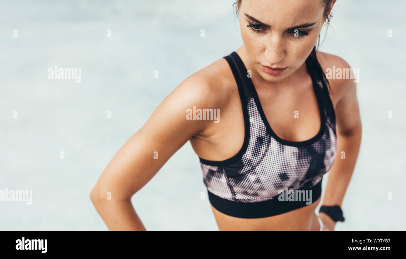 Donna prendendo pausa dopo formazione sportiva. Donna in piedi con le mani sui fianchi che guarda lontano. Foto Stock