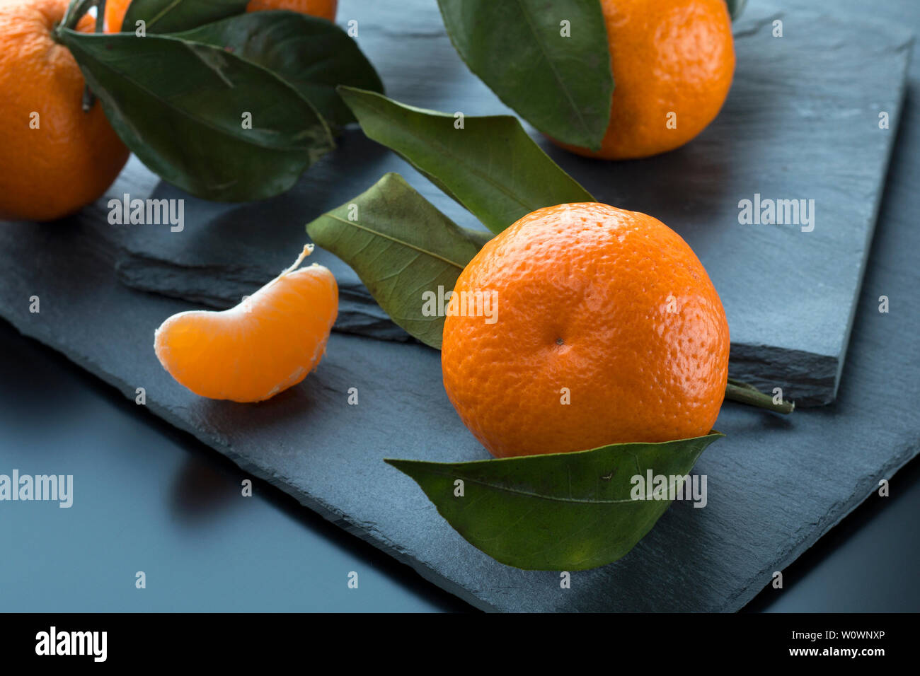 Mandarini con foglie in ardesia scura sullo sfondo della piastra. Messa a fuoco selettiva Foto Stock