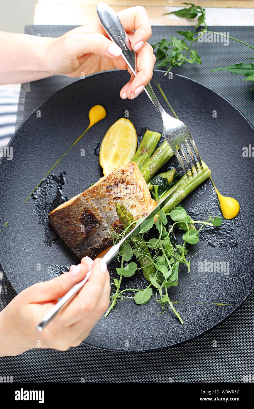 Una donna è mangiare un piatto in un ristorante. Foto Stock