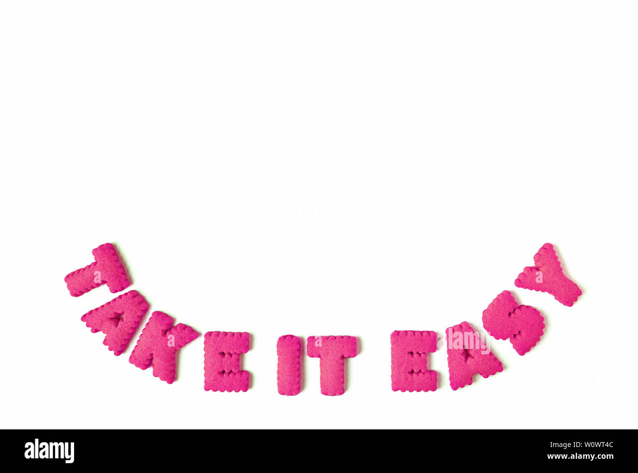 La vibrante rosa a forma di alfabeto cookies l'ortografia della parola Take it easy su sfondo bianco Foto Stock