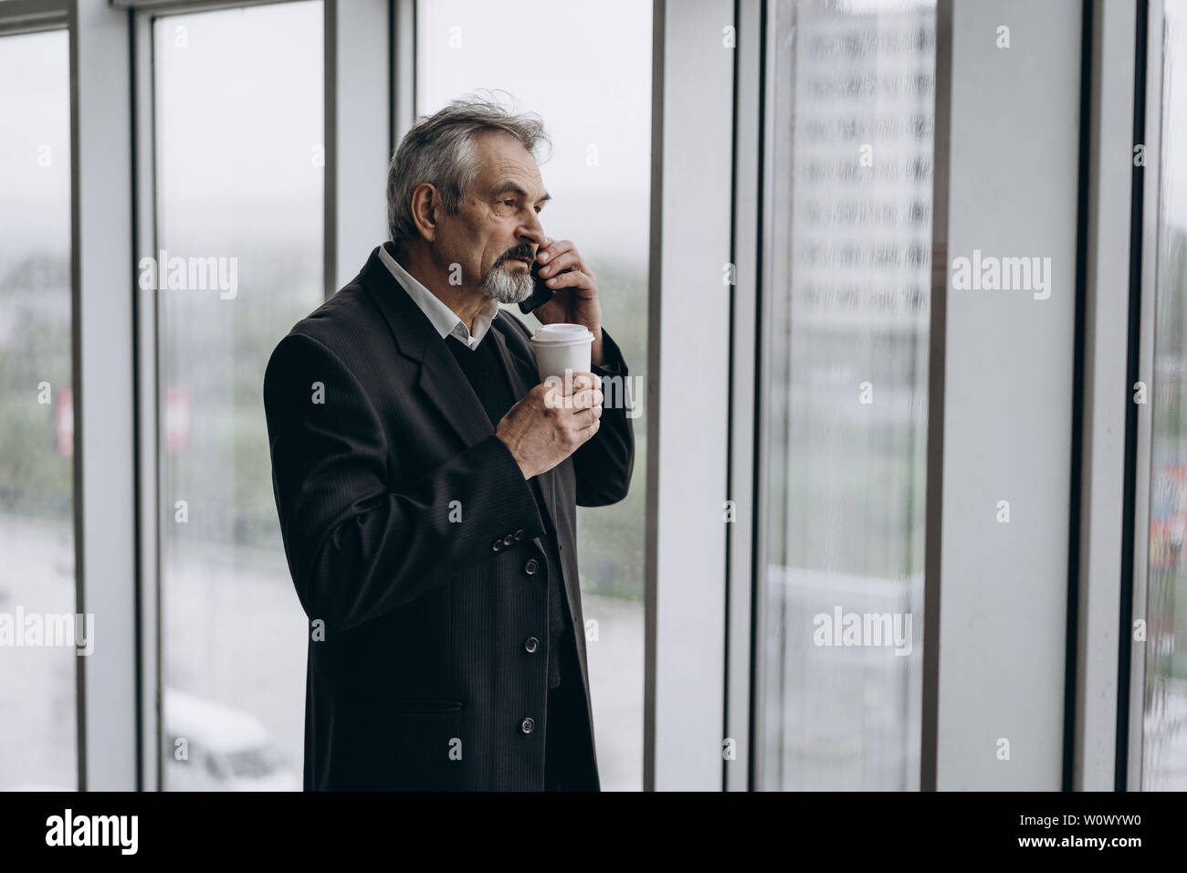 Di mezza età uomo d affari con lo smartphone. Nel grande business center. L'uomo anziano Foto Stock