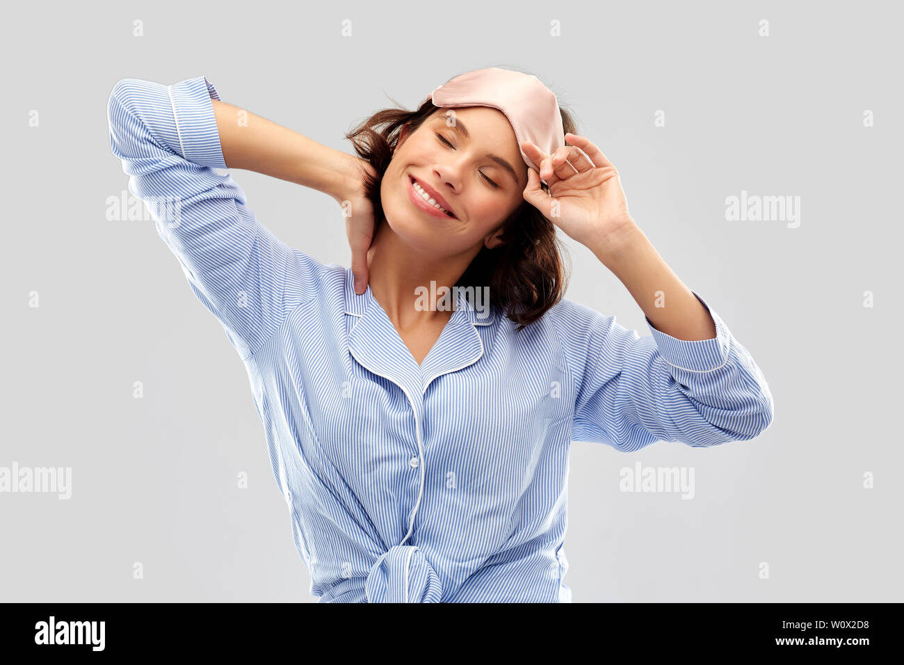 Felice giovane donna in pigiama e occhio maschera del sonno Foto Stock