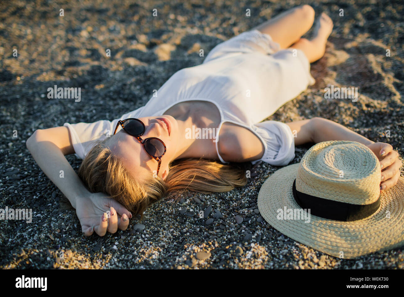 Estate donna rilassante, giacente nella sabbia in spiaggia, indossando occhiali da sole. Ragazza divertirsi durante i viaggi vacanze vacanza. Foto Stock