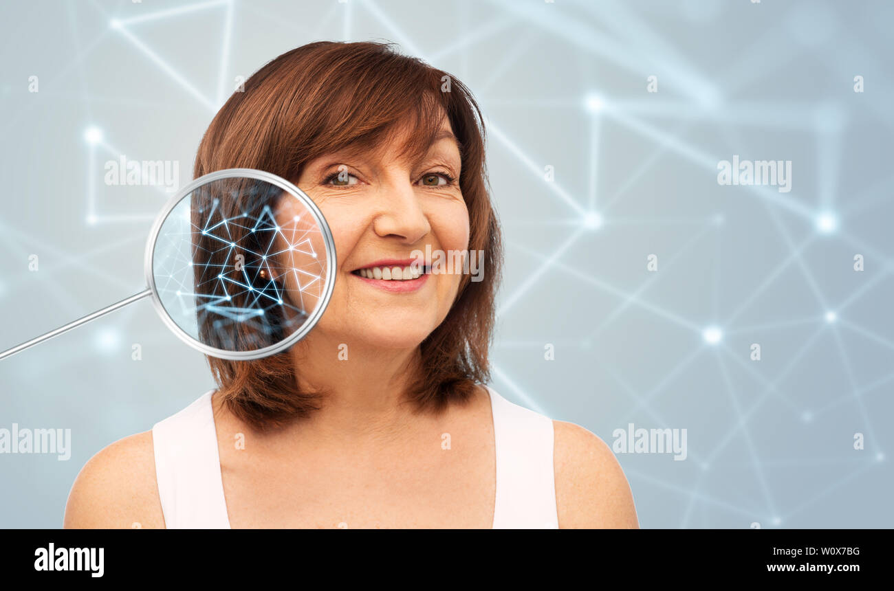 Donna senior con bassa poli grid in magnifier Foto Stock