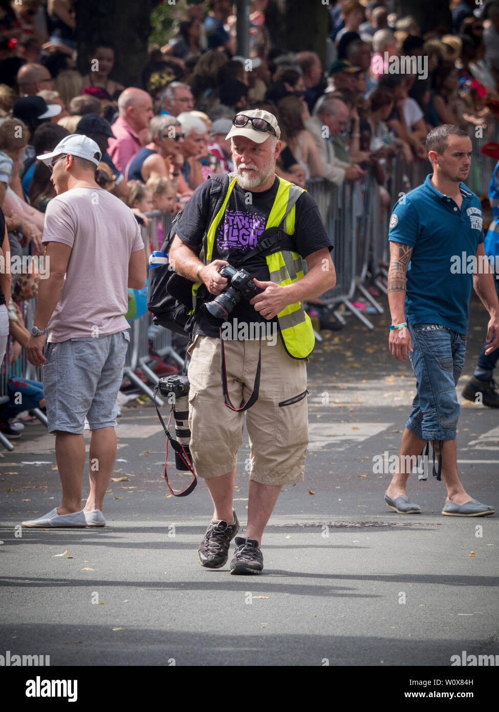 Gazzetta fotografo di eventi che indossa hi-vis e portante due telecamere professionali Foto Stock