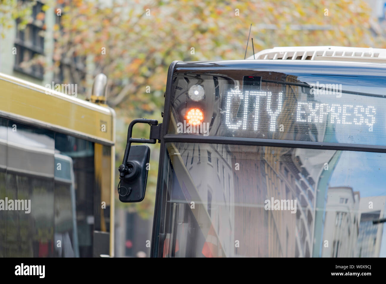 Due città gli autobus di " commuters " passando in una strada con alberi d'autunno in background e le parole City Express mostra sulla parte anteriore di un bus Foto Stock