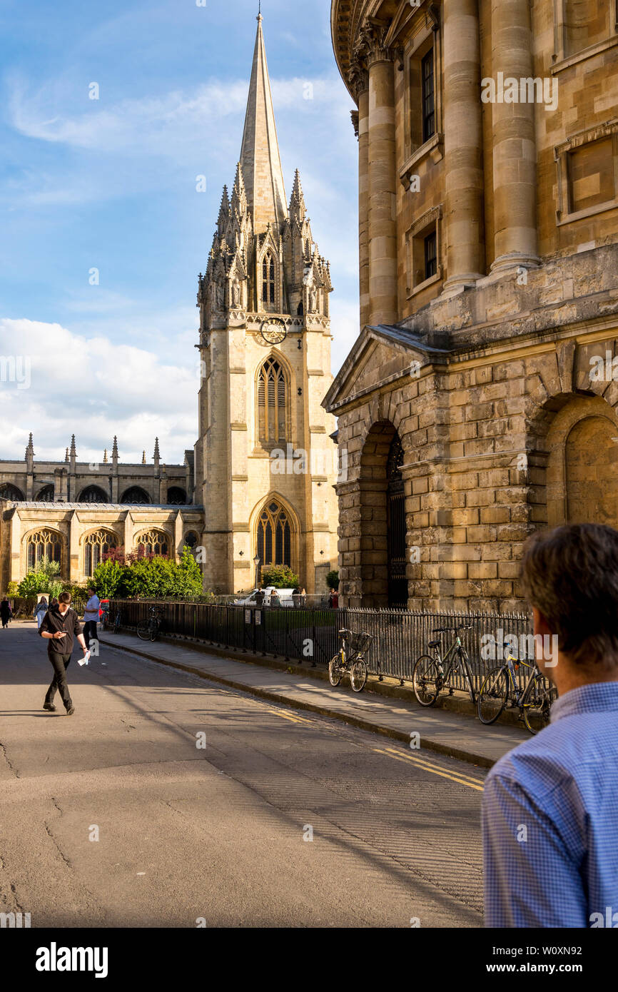 Una bella sera d'estate nella famosa città universitaria di Oxford. Una vista del soleggiato luminosamente St Mary's Church e Radcliffe Camera in ombra. Foto Stock