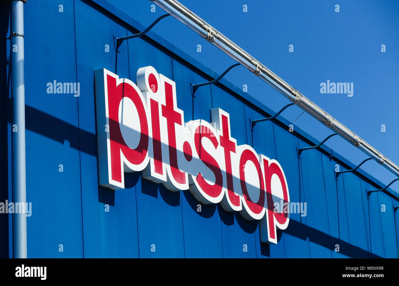 TOENISVORST, Germania - juin 28. 2019: Close up red pit stop (pitstop) il logo sulla parete blu con il blu del cielo (tedesco repair shop catena) Foto Stock